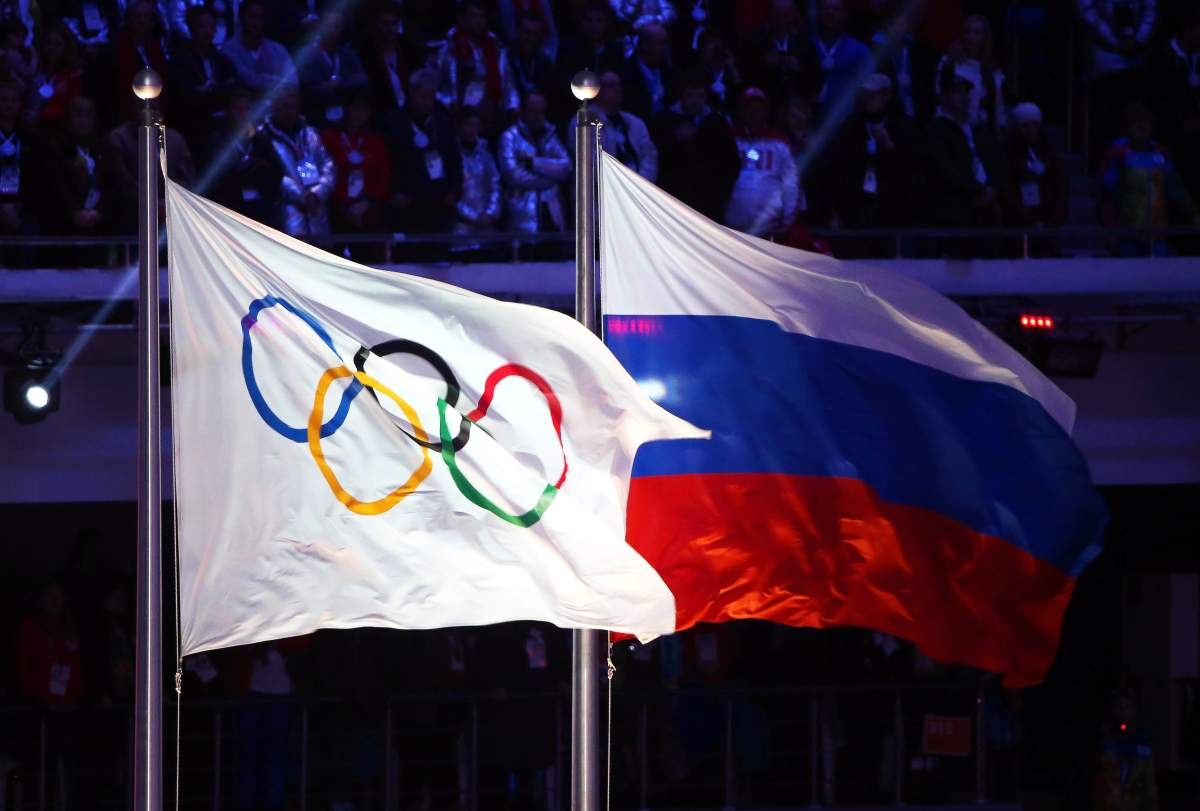 The Olympic flag (L) and the Russian flag (R) fly during the closing ceremony of the Sochi 2014 Olympic Games at Fisht Olympic Stadium in Sochi, Russia, in 2014.