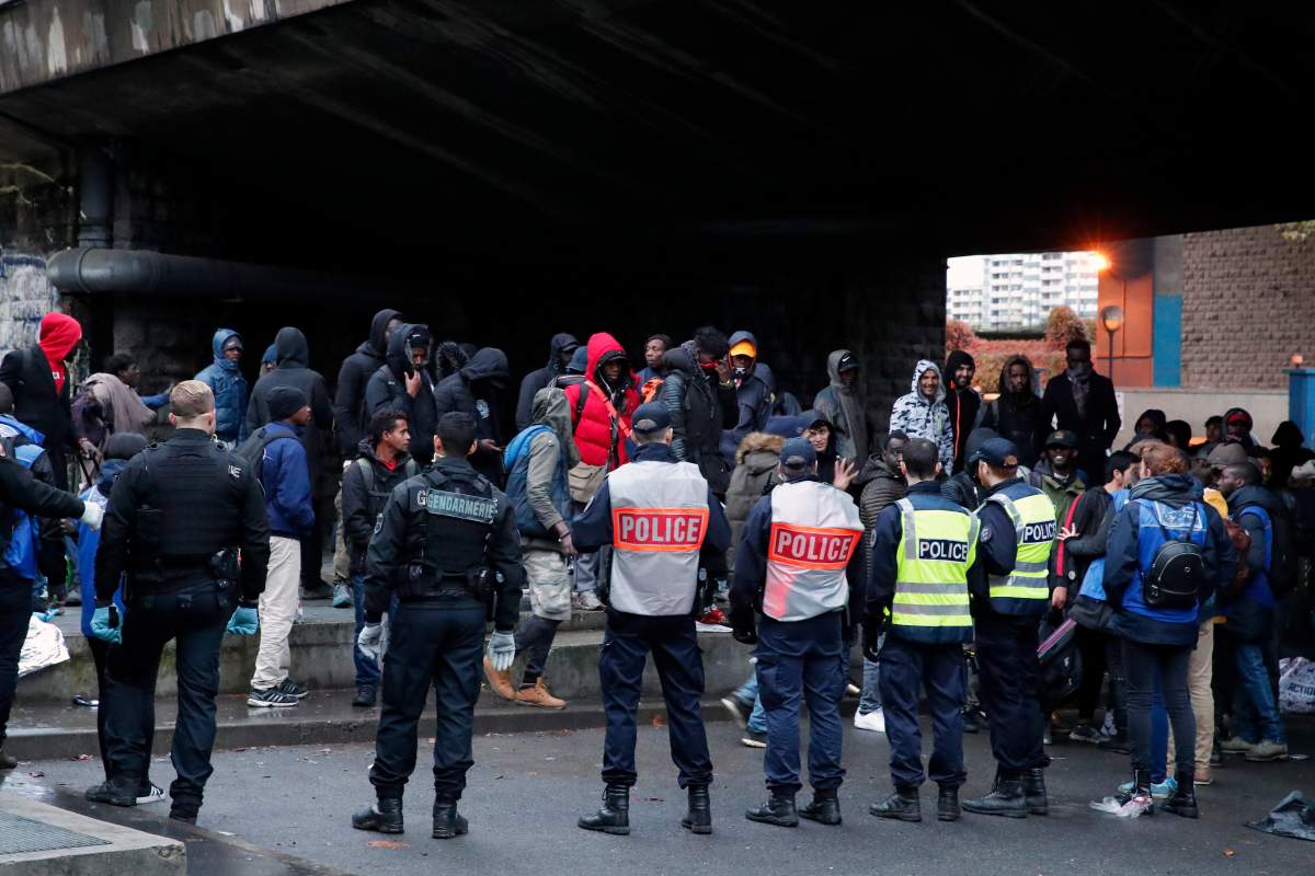 French Police officers control migrants during a large operation to dismantle makeshift migrant camps in the north of Paris, Thursday, Nov. 7, 2019. (AP Photo/Francois Mori)