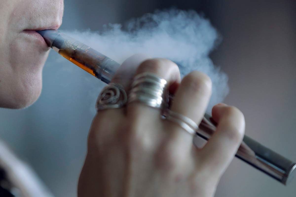 In this Friday, Oct. 4, 2019 file photo, a woman using a vaping device exhales a puff of vapour in Mayfield Heights, Ohio.