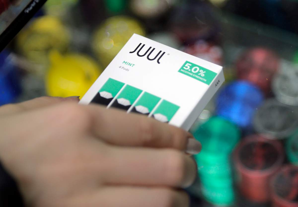FILE - In this Dec. 20, 2018, file photo a woman buys refills for her Juul at a smoke shop in New York.