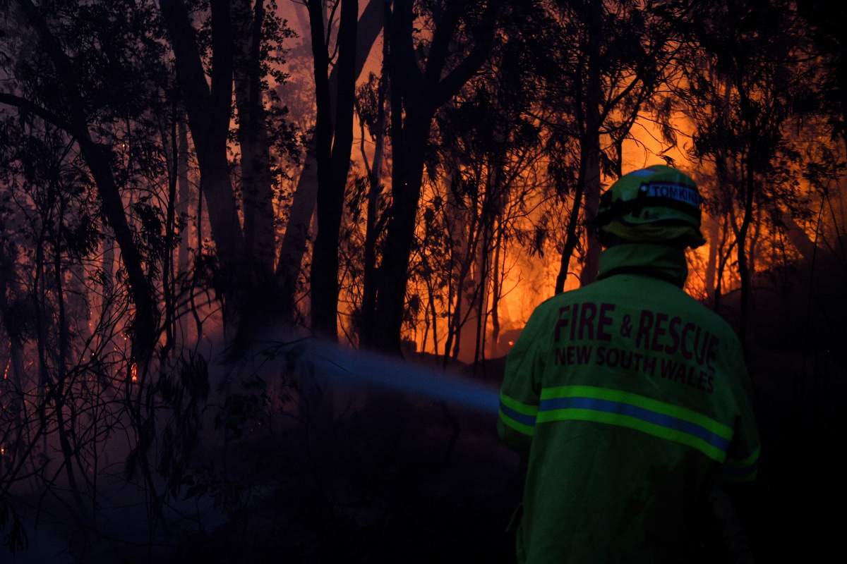 Fire and Rescue NSW firefighters conduct property protection as a bushfire burns close to homes on Railway Parade in Woodford NSW, Friday, Nov. 8, 2019. (Dan Himbrechts/AAP Image via AP)