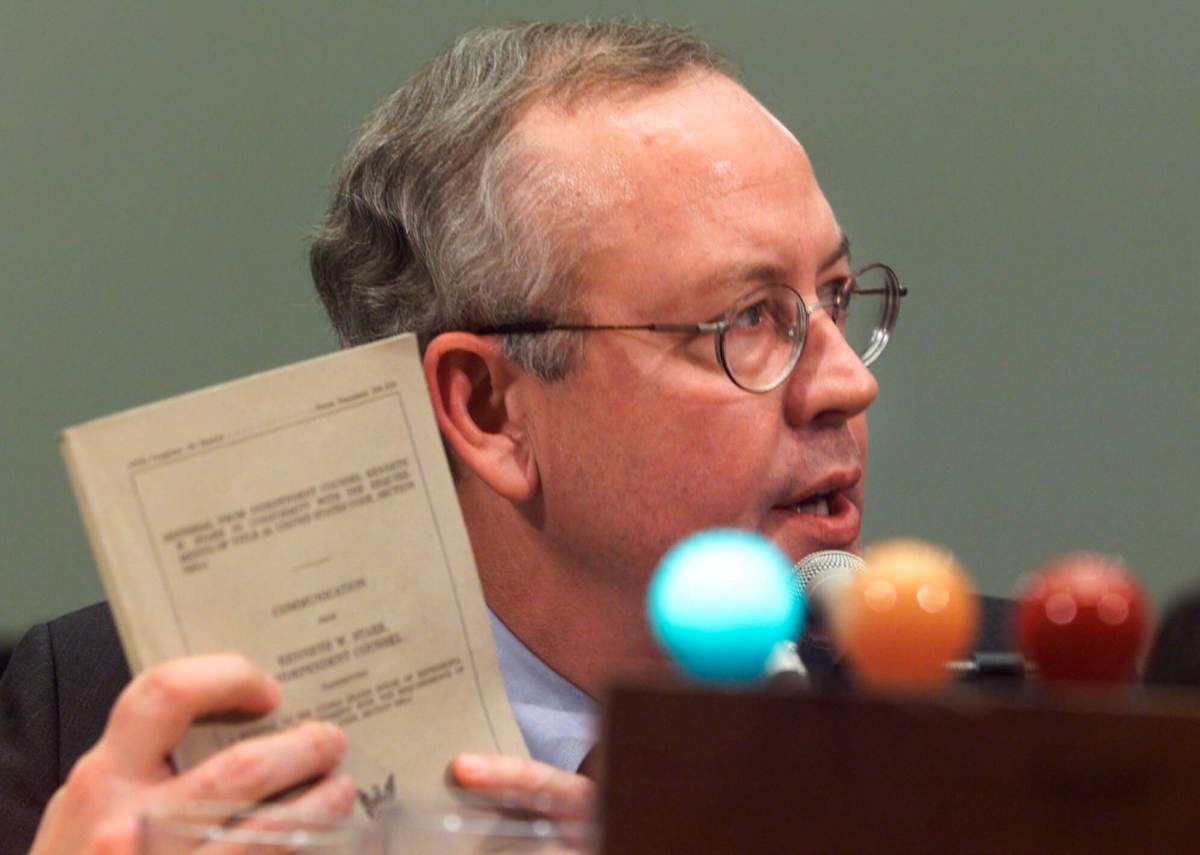 In this Nov. 19, 1998 file photo, Independent Counsel Kenneth Starr holds up his report while testifying on Capitol Hill, before the House Judiciary Committee’s impeachment hearing. (AP Photo/Joe Marquette)