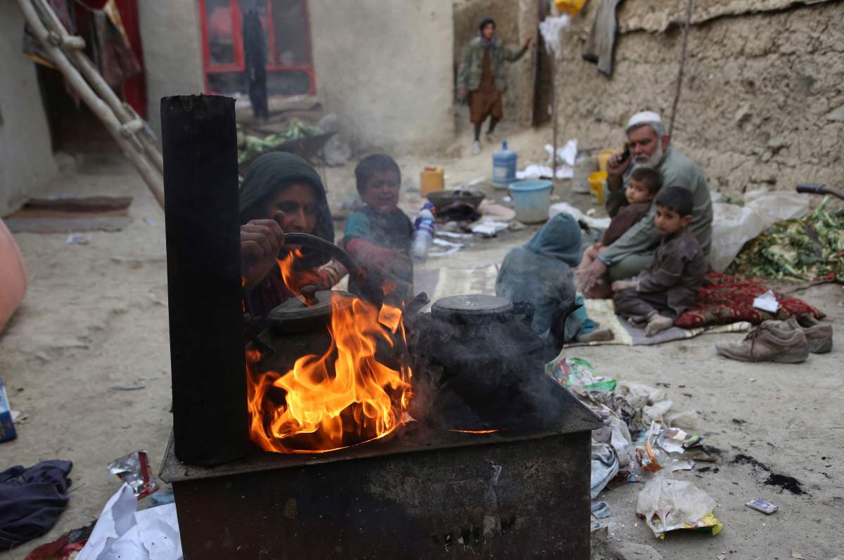 Yousuf, who fled with his family from his home in eastern Afghanistan eight years ago to escape the war, sits with children while his wife burns plastic as she makes tea, in Kabul, Afghanistan on Oct. 29, 2019.