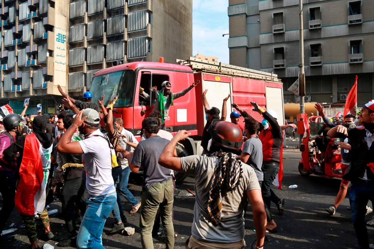 Anti-Government protesters prevent a fire truck from extinguishing a fire in a building during clashes between Iraqi security forces and demonstrators, in Baghdad, Iraq, Thursday, Nov. 14, 2019.