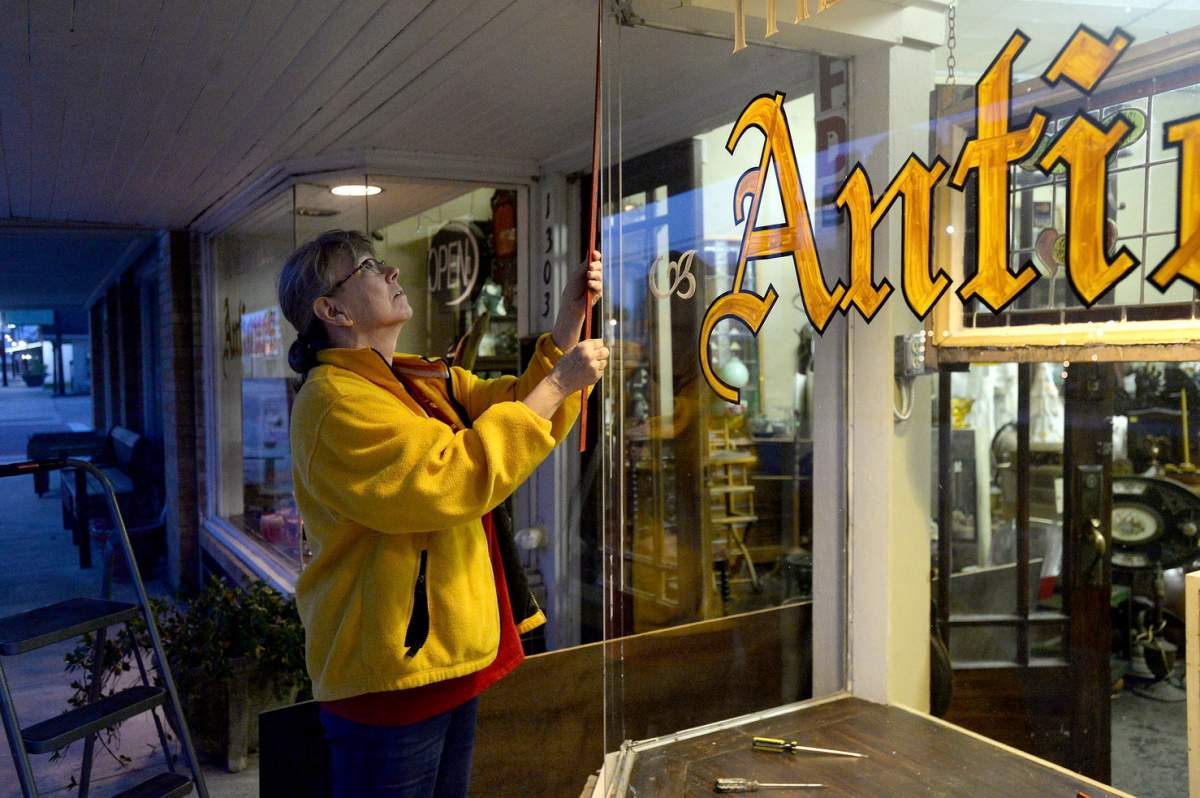 The Yellow Rose antique store owner Ellen Warner measures the frame where a storefront window shattered caused by the explosion. (Kim Brent/The Beaumont Enterprise via AP)
