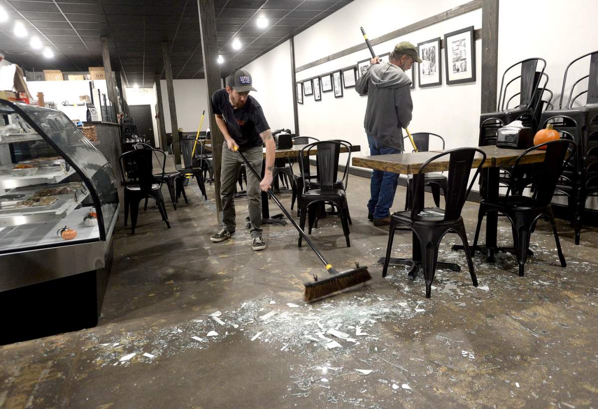 Robert and David Pool sweep up the glass filling the floor and tabletops at The Avenue Coffee Shop after the business’ front windows shattered following an explosion at the TPC plant. (Kim Brent/The Beaumont Enterprise via AP)