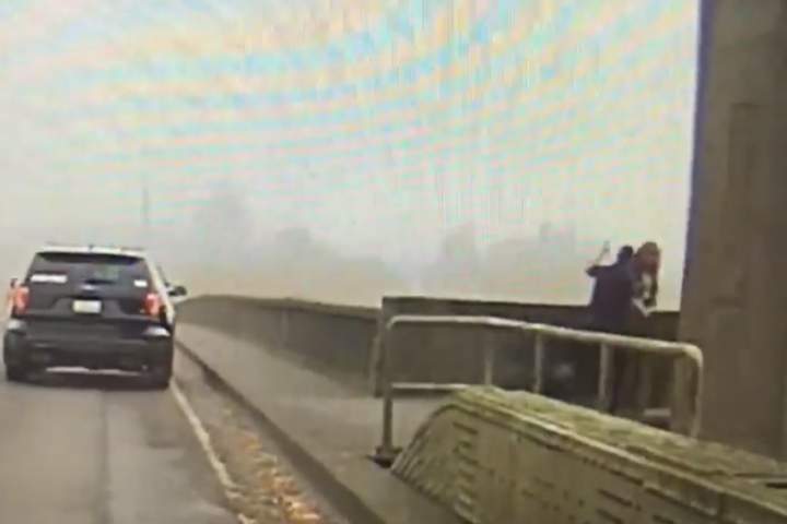 This image from a dashcam video shows a Cosmopolis police officer preventing a woman from climbing over the central span of the Chehalis River Bridge near Aberdeen, Wash., on Nov. 2, 2019.