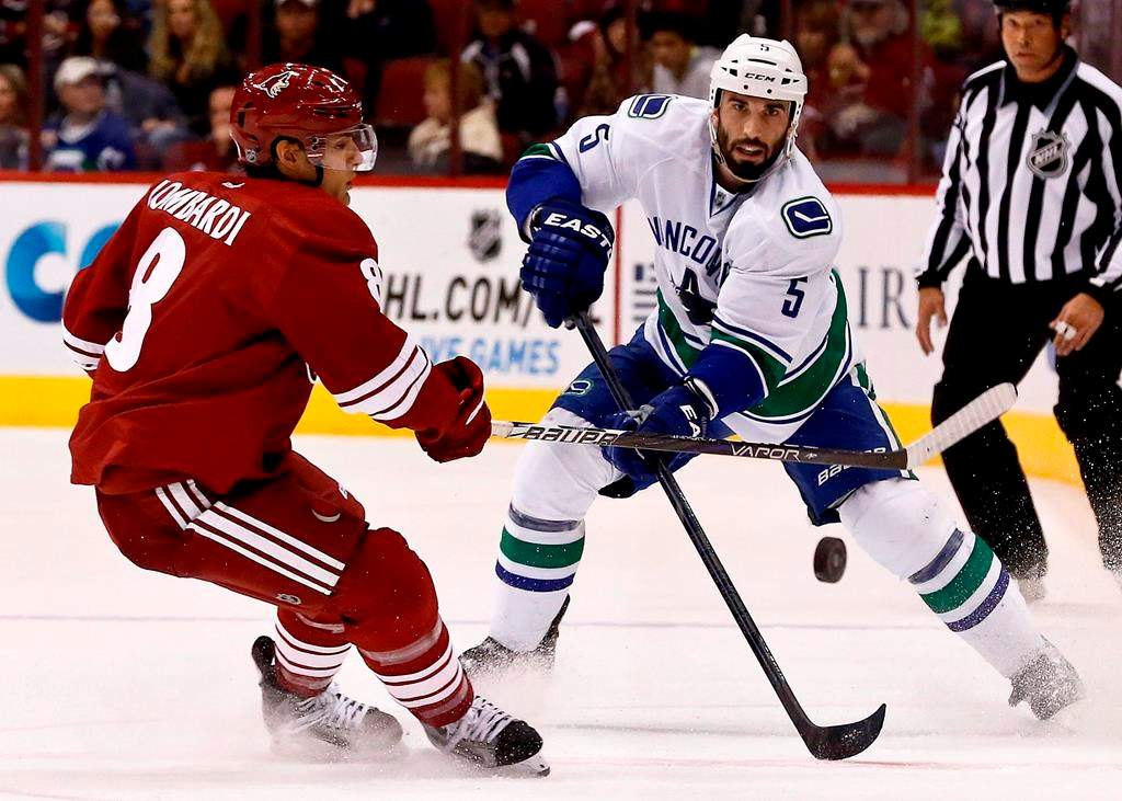 Vancouver Canucks' Jason Garrison (5) passes the puck in front of Phoenix Coyotes' Matthew Lombardi, left, during the first period in an NHL hockey game on Thursday, March 21, 2013, in Glendale, Ariz. A former National Hockey League defenceman is suing his financial adviser claiming negligent advice led to investment decisions that cost far more than the multimillion-dollar salary he earned during a six-year contract with the Vancouver Canucks.