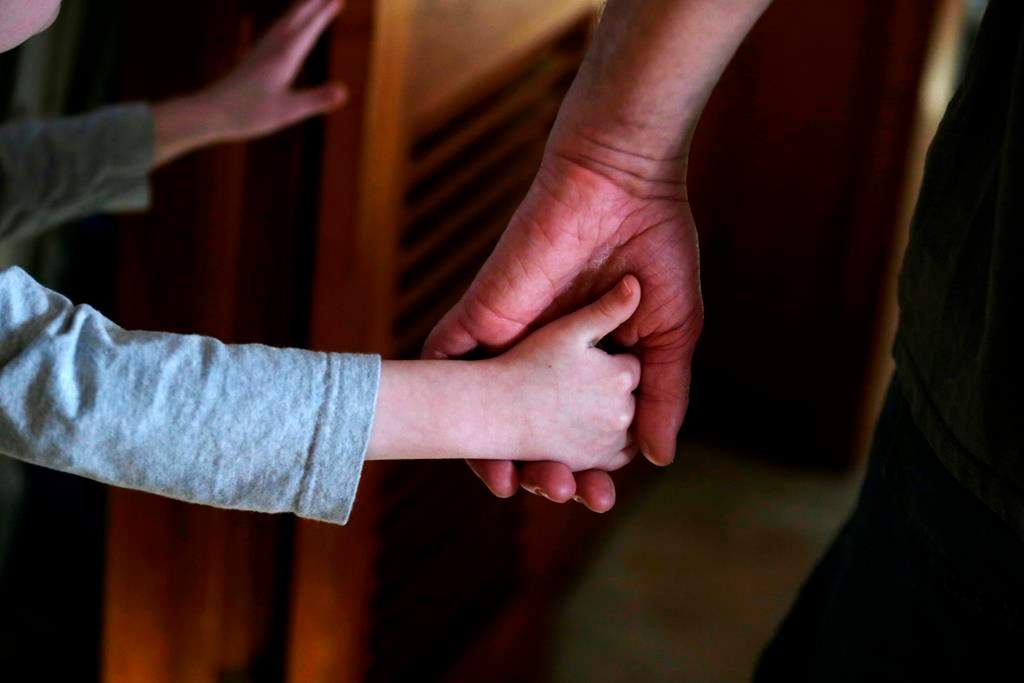 A child is shown holding an adult's hand.