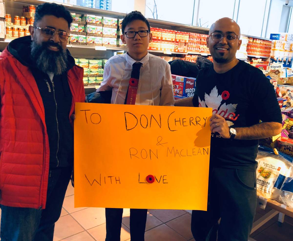 Ammar Naseer, right, holds a sign directed at Don Cherry and Ron MacLean with two others inside a Loblaws in Mississauga, Ont.