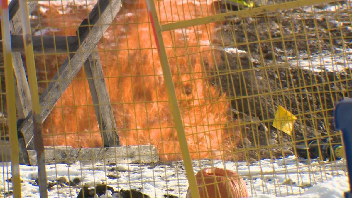 Flames shoot from a pit at the site of a gas line fire in Calgary.