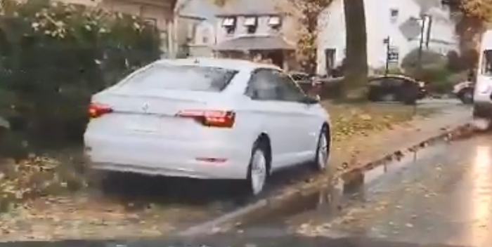 A white car can be seen driving up on the sidewalk in Toronto to get around traffic.