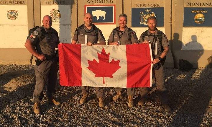 Staff Sgt. Nolan Berg (second from the left) and others pose with a Canadian flag on Sept. 11.