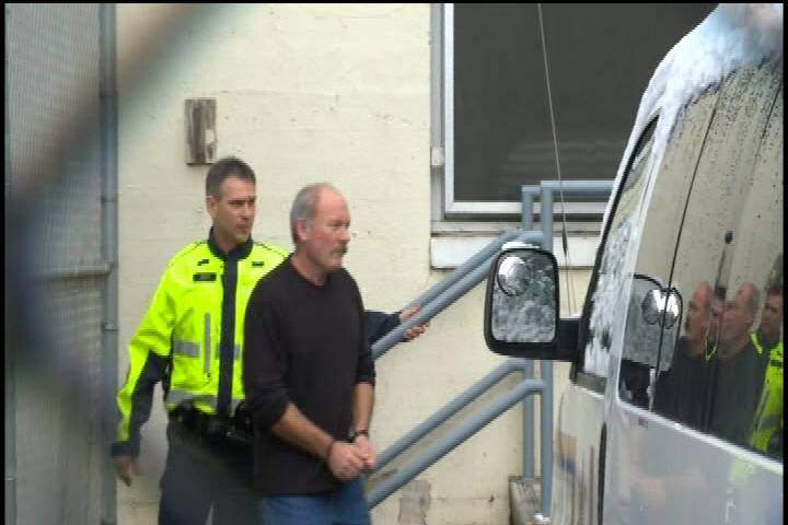 Former RCMP officer Keith Wiens escorted by a sheriff during his court proceedings.