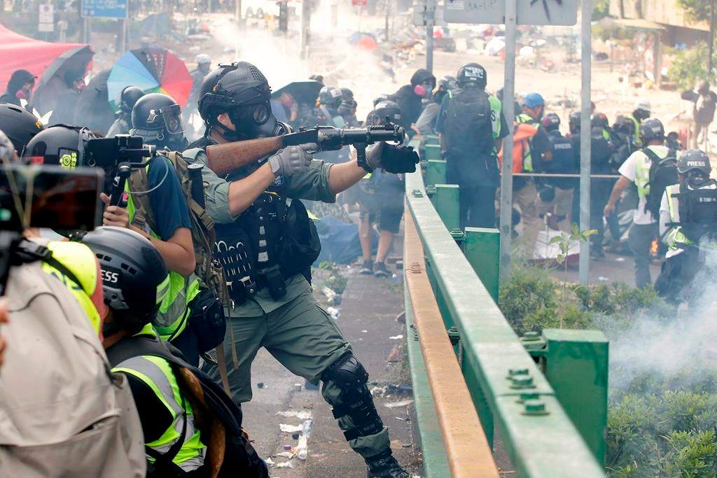 A police officer prepares to fire tear gas canisters during a clash with protestors near the Hong Kong Polytechnic University in Hong Kong, Monday, Nov. 18, 2019. Hong Kong police have swooped in with tear gas and batons as protesters who have taken over a university campus make an apparent last-ditch effort to escape arrest. (AP Photo/Achmad Ibrahim).