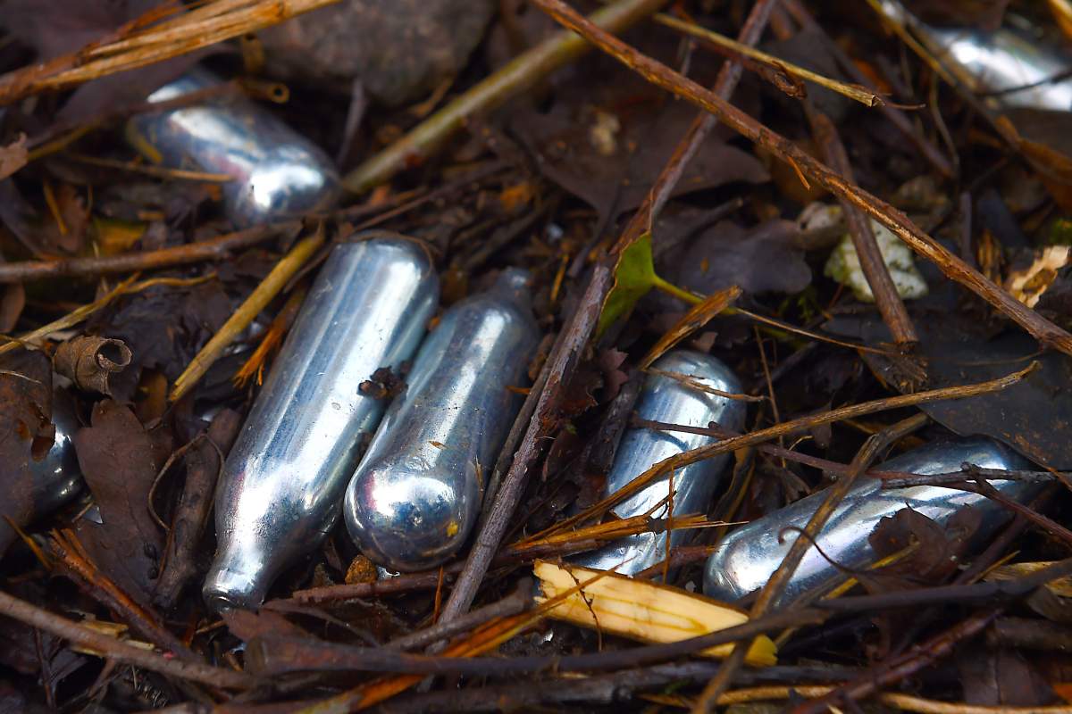 Used canisters of nitrous oxide lie on the ground.