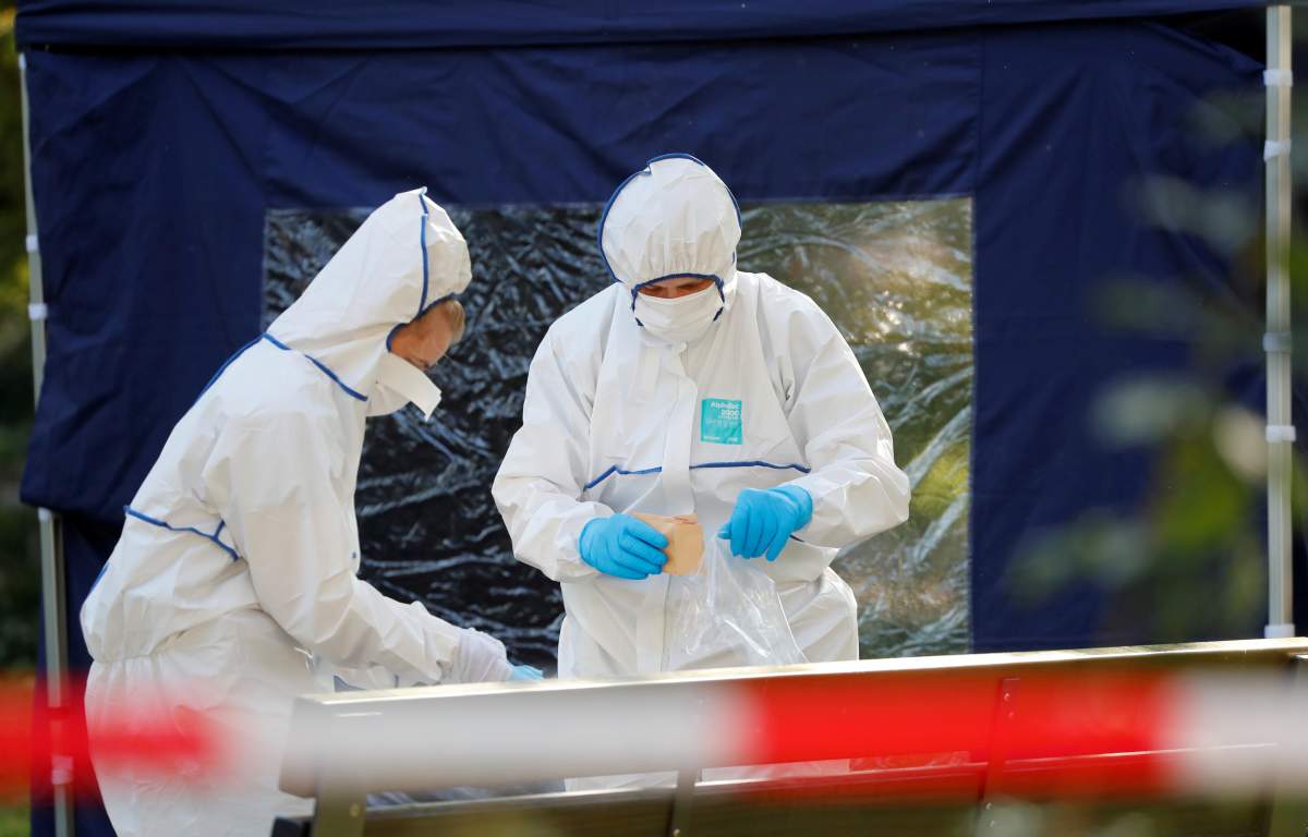 Police officers investigate a crime scene in Berlin, Germany, Aug. 23, 2019, after a cyclist shot at a man in the Moabit district.