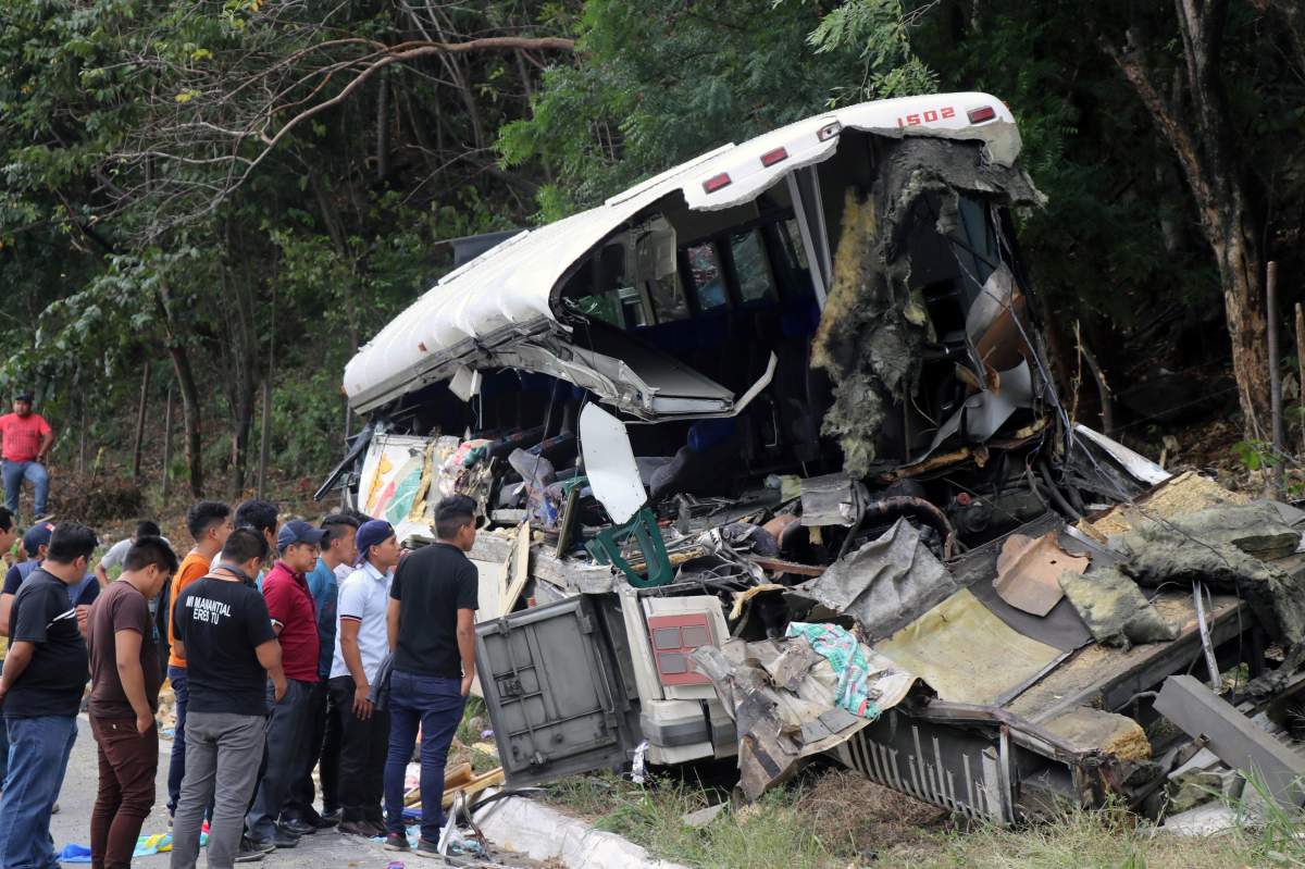 People are pictured on the scene of a collision between a passenger bus and a trailer truck early on Saturday in Gualan, near Guatemala’s Atlantic coast, Guatemala, on Dec. 21, 2019.