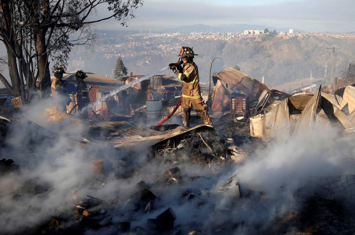 Firefighters work to extinguish a fire following the spread of wildfires in Valparaiso, Chile, Dec. 24, 2019.