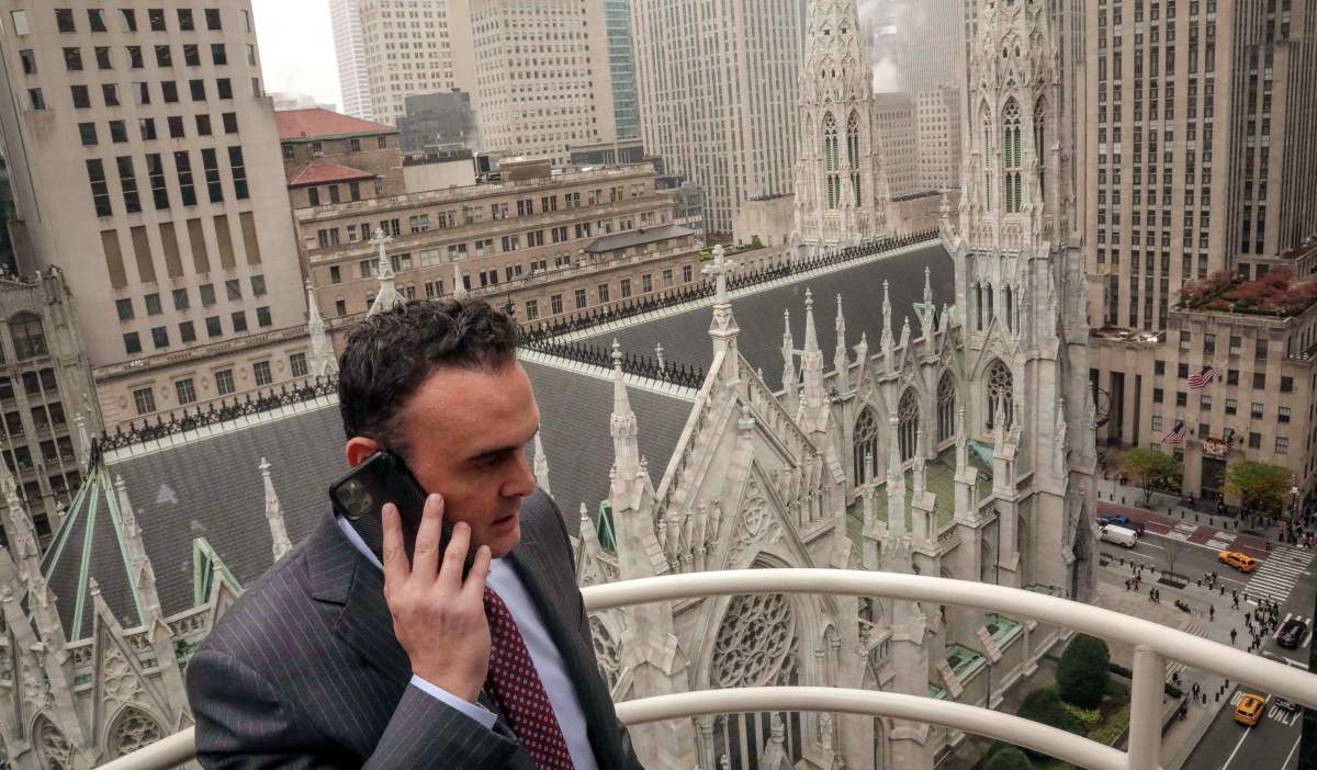 In this Tuesday, Oct. 29, 2019, photo, attorney Adam Slater takes a phone call on a patio outside his high-rise Manhattan office overlooking St. Patrick’s Cathedral, in New York. Slater’s firm is representing clients accusing the Roman Catholic Church of sexual abuse, a clientele that is rapidly growing after New York state opened its one-year window allowing sex abuse suits with no statute of limitations. (AP Photo/Bebeto Matthews)