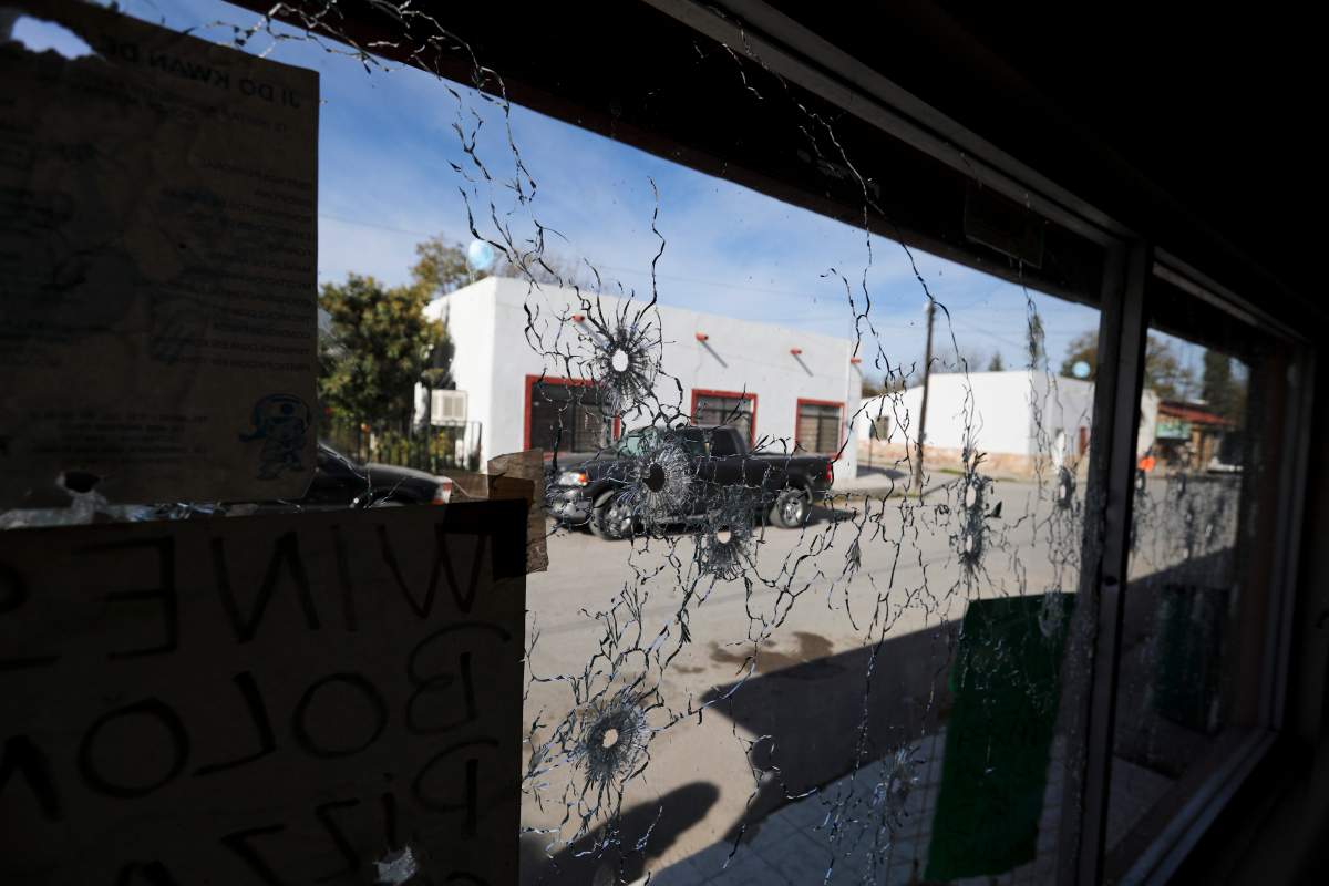 A shop’s windows are riddled with bullet holes near City Hall after a gunbattle in Villa Union, Mexico, Dec. 2, 2019.