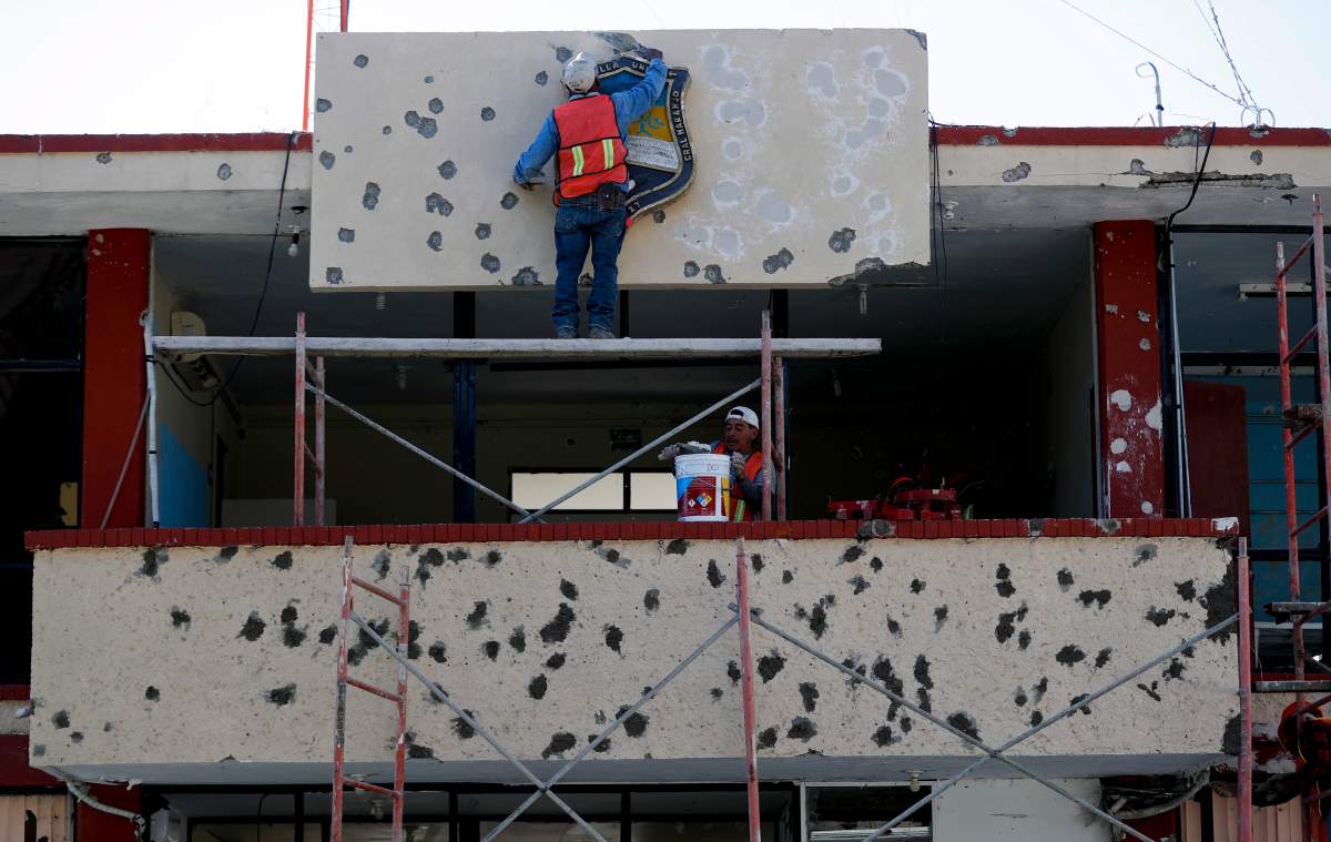 Workers repair the facade of City Hall riddled with bullet holes, in Villa Union, Mexico, Dec. 2, 2019.