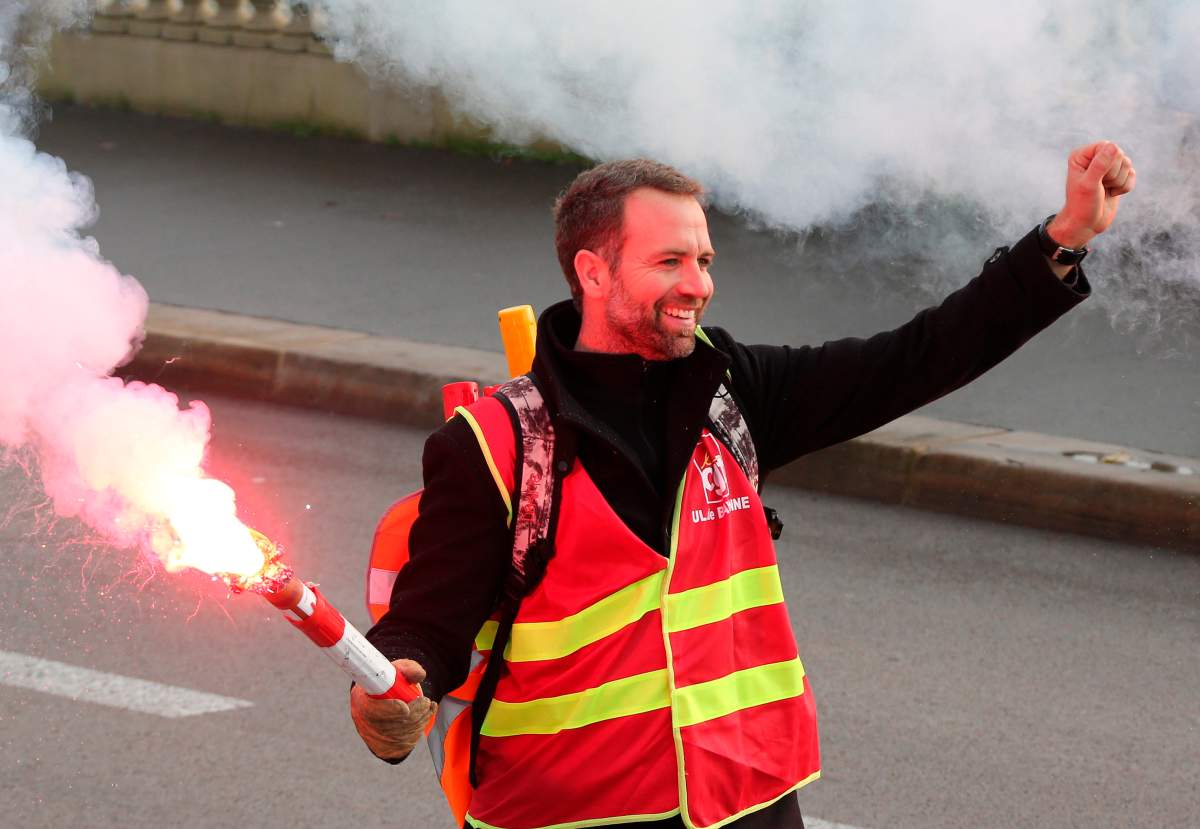 A demonstrator walks on with raised fist in Bayonne, southwestern France, Thursday, Dec.5, 2019. Transport will be hardest hit by the walkout, with flights, trains and buses canceled and most of the Paris subway system coming to a halt. (AP Photo/Bob Edme)