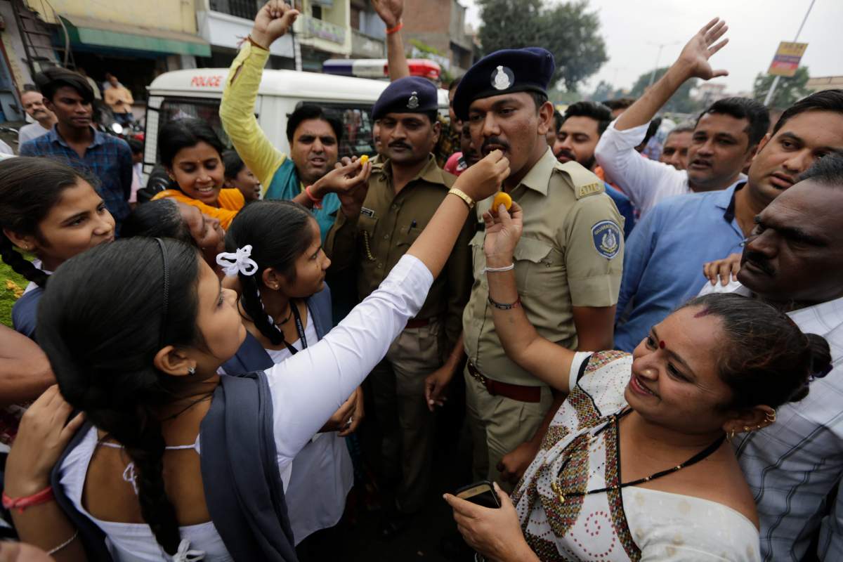 Indian feed sweets to policemen on duty and shout slogans in favor of police to celebrate killing of four men suspected of raping and killing a woman in Shadnagar in southern state of Telangana, in Ahmadabad, India, Friday, Dec. 6, 2019.