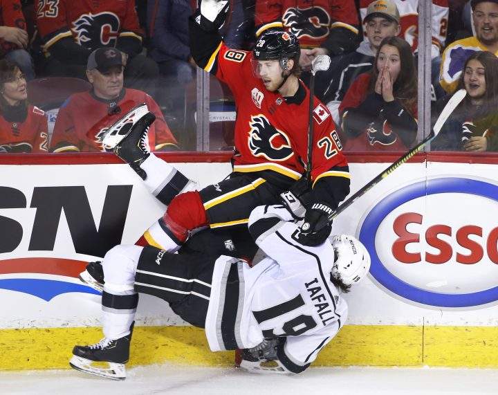 Los Angeles Kings’ Alex Iaffalo, bottom, takes a hit from Calgary Flames’ Elias Lindholm, of Sweden, during third period NHL hockey action in Calgary, Alta., Saturday, Dec. 7, 2019.