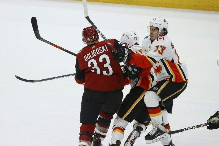 Arizona Coyotes defenseman Alex Goligoski (33) checks Calgary Flames center Derek Ryan (10) and Flames left wing Johnny Gaudreau (13) during the third period of an NHL hockey game Tuesday, Dec. 10, 2019 in Glendale, Ariz. The Flames defeated the Coyotes 5-2.