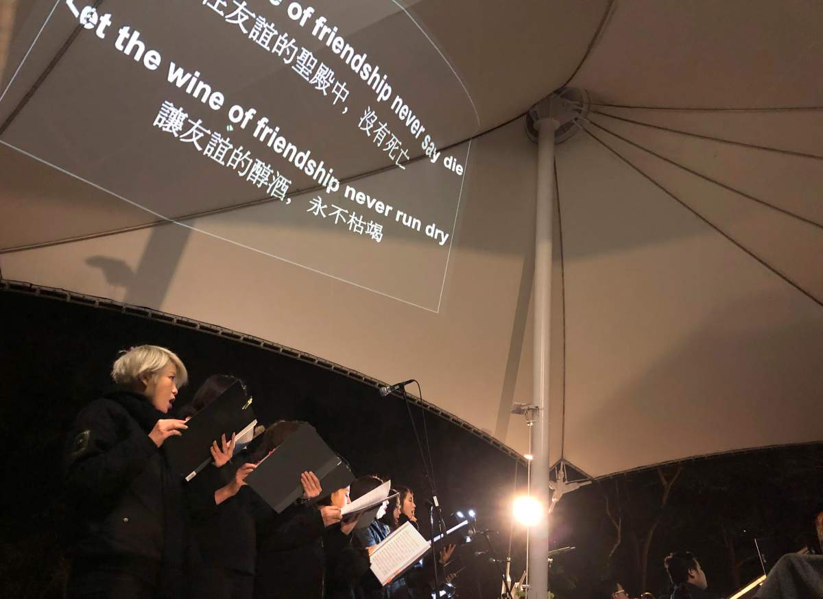 In this Dec. 10, 2019 photo, lyrics are projected on a canopy as a theatre troupe performs Les Miserables in at an outdoor event space in Hong Kong.