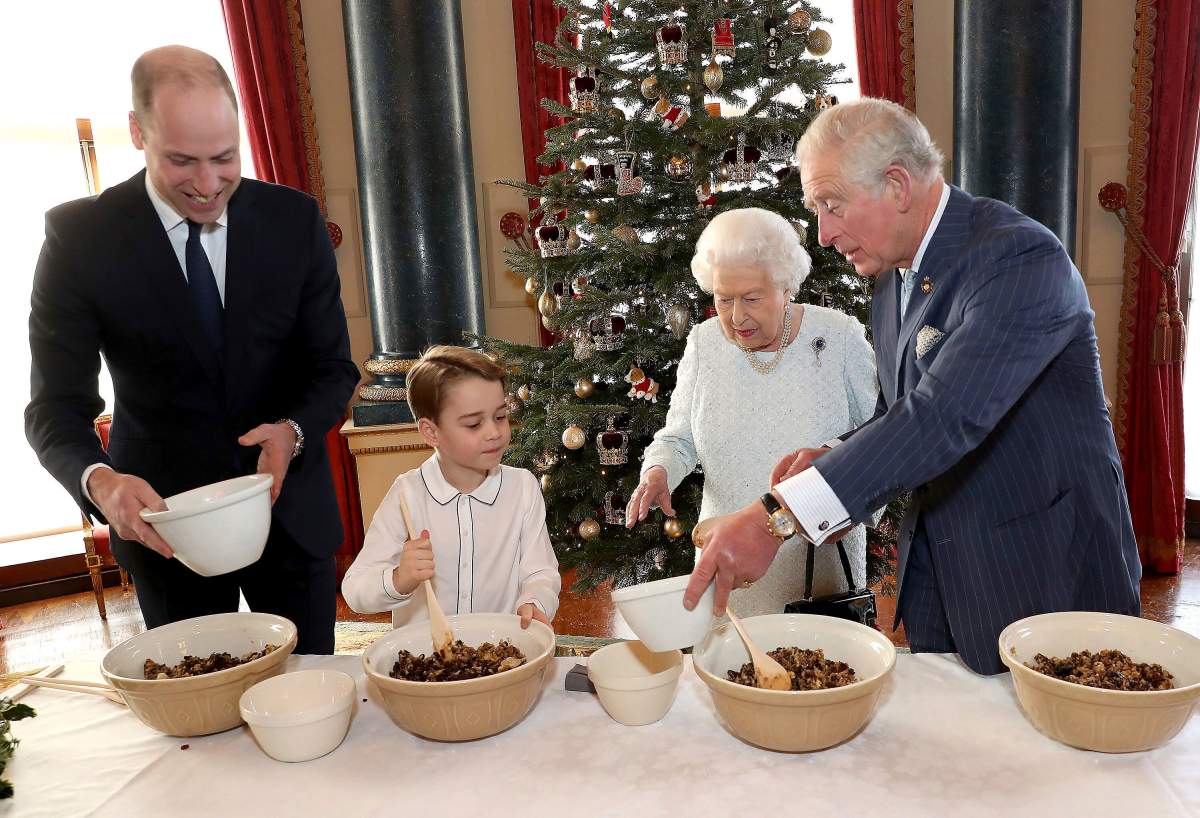 In this undated photo provided by Buckingham Palace, Britain’s Queen Elizabeth, Prince Charles, Prince William and Prince George smile as they prepare special Christmas puddings in the Music Room at Buckingham Palace, London, as part of the launch of The Royal British Legion’s Together at Christmas initiative.