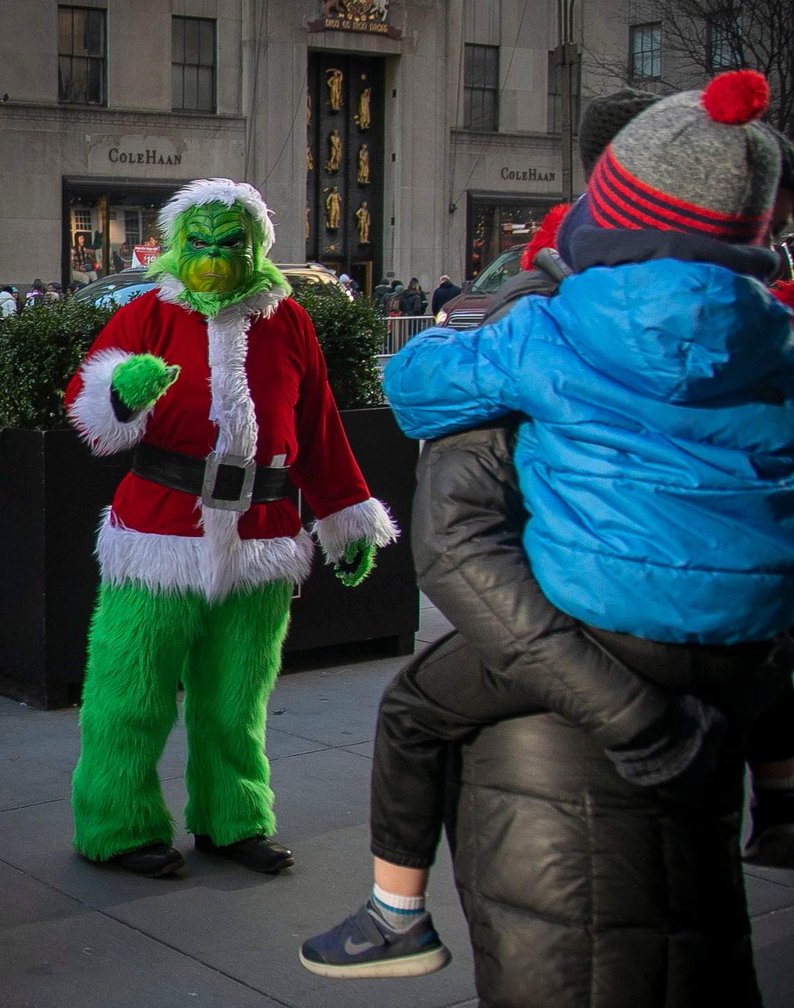 In this Dec. 20, 2019 photo, a costumed Grinch performer, left, works a sidewalk poses for a photo along 5th Avenue near Rockefeller Center in New York.