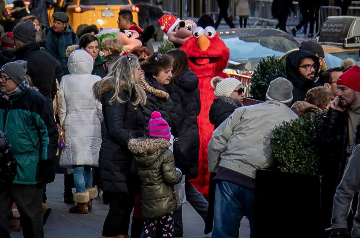 In this Dec. 20, 2019 photo, a costumed Elmo performer works a sidewalk for tips along 5th Avenue near Rockefeller Center in New York.