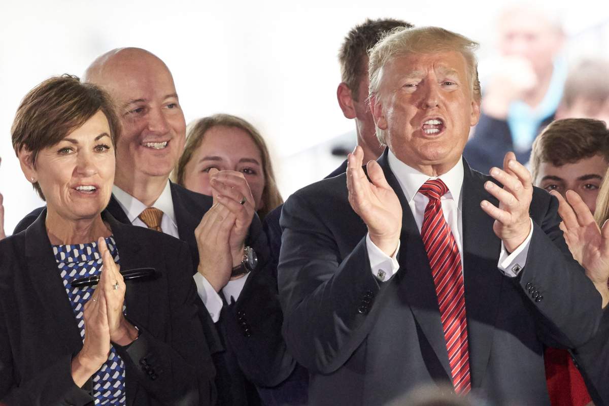 In this June 11, 2019 photo, President Donald Trump applauds next to Governors Pete Ricketts of Nebraska, second left, and Kim Reynolds of Iowa, left, in Council Bluffs, Iowa.