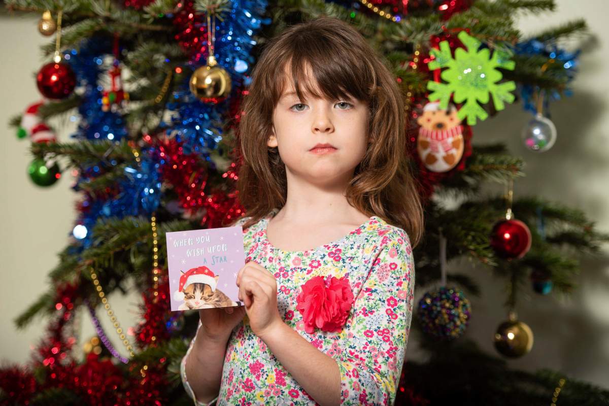 Florence Widdicombe, 6, poses with a Tesco Christmas card from the same pack as a card she found containing a message from a Chinese prisoner, in London, Sunday, Dec. 22, 2019.