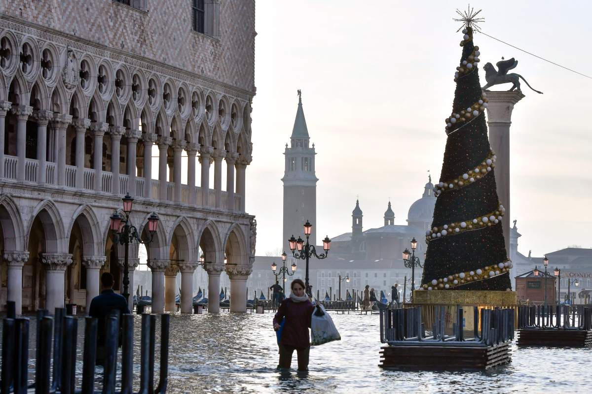 A woman wades through high water during a high tide of 1.44 meters (4.72 feet), in St. Mark’s Square, in Venice, Italy, Monday, Dec. 23, 2019.