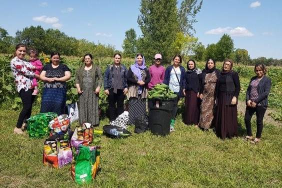 Yazidi refugees pose with some vegetables they grew in a handout photo. Hundreds of other Yazidi refugees, harvested more than 9,000 kilograms of produce this year as part of a special farming project in Manitoba. 