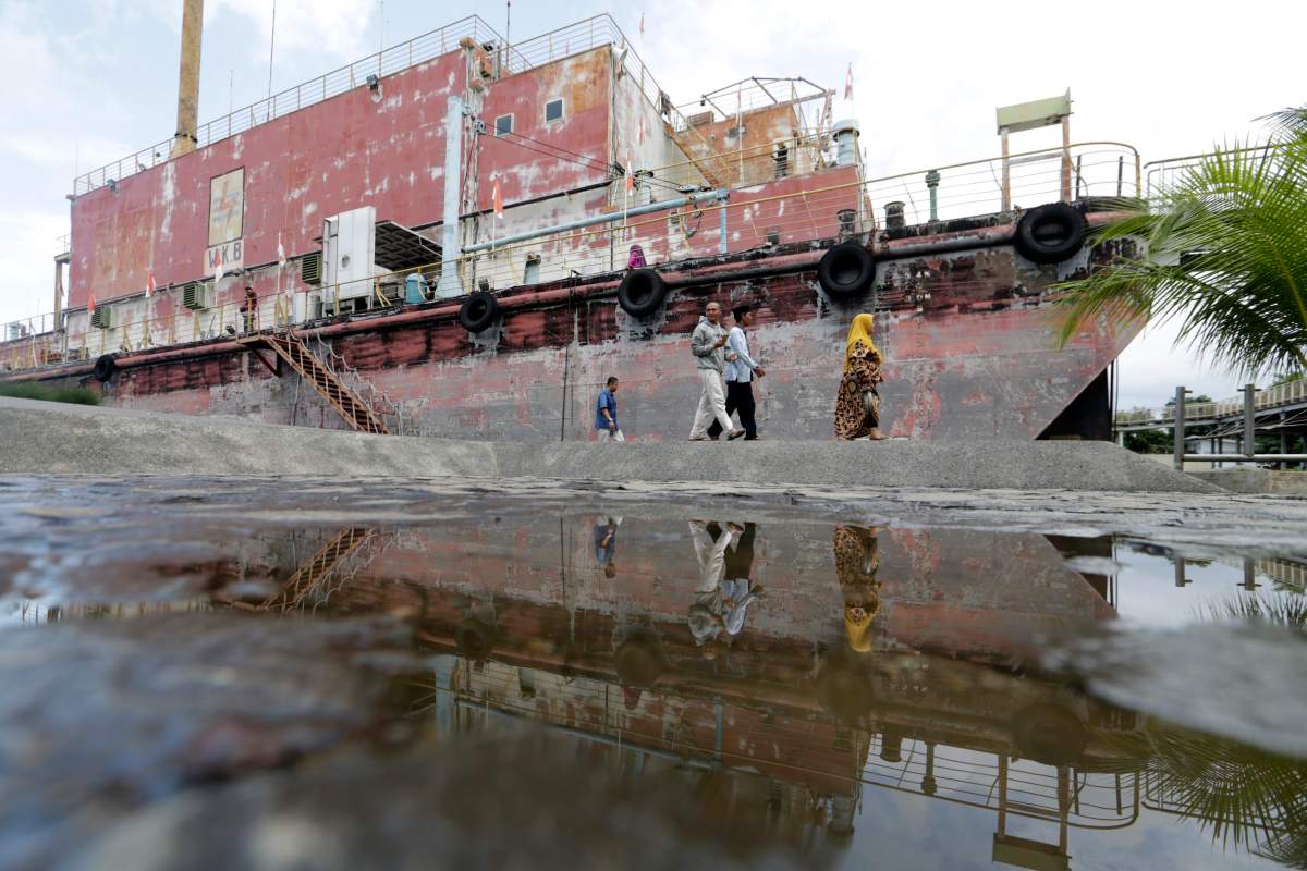 Visitors view a power plant boat that was stranded on land by the Boxing Day tsunami in Punge Jurong, Banda Aceh, Indonesia, 20 December 2019.