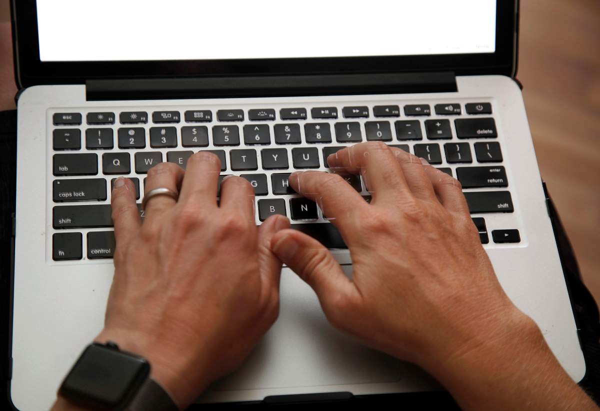 A person works on a laptop in North Andover, Mass., June 19, 2017 file photo. An annual review of how well the government interacts with Canadians applying or managing federal benefits suggests more people would turn to online channels, but only if there was a human around to help them out. 