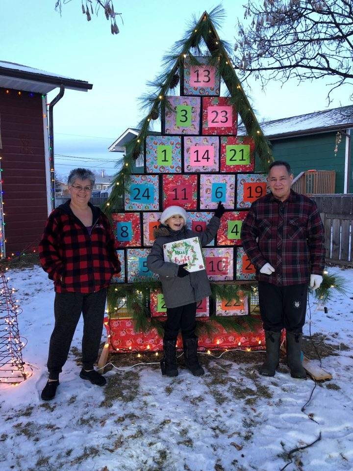 Brenda Morin, her grandson Chance Hodgson and her husband Harold stand in front of their calendar.