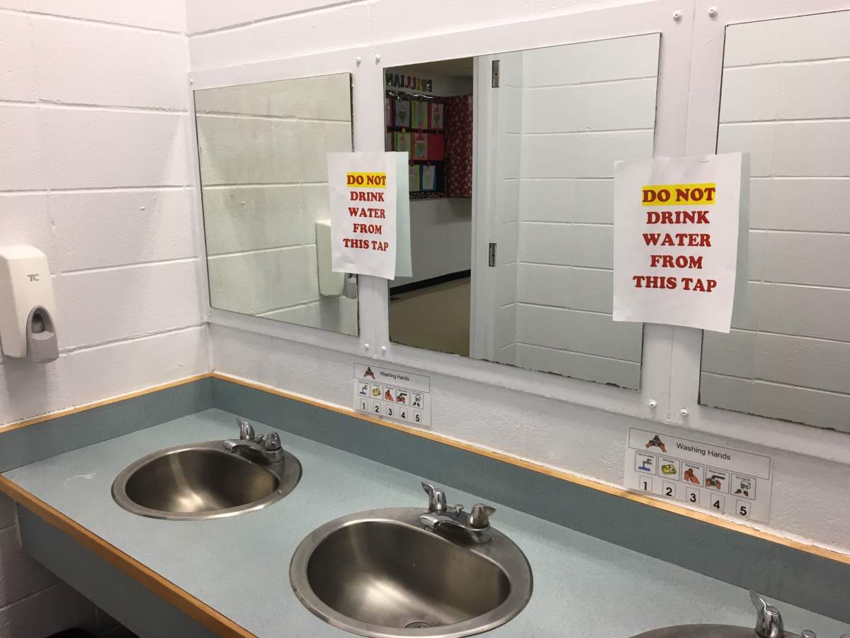Signs warning students to avoid the water are posted above the bathroom sinks inside Condor School.