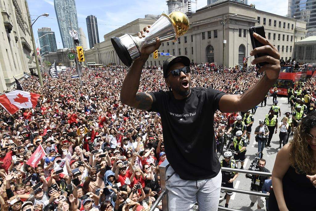 Toronto Raptors forward Kawhi Leonard takes a selfie holding his playoffs MVP trophy as he celebrates during the 2019 Toronto Raptors Championship parade in Toronto on Monday, June 17, 2019.