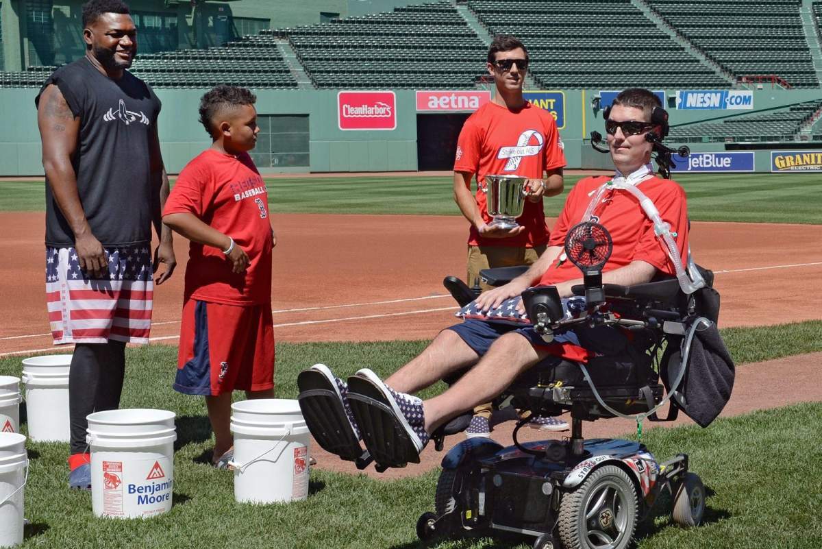 In this file photo, former Boston College baseball player Pete Frates passes Boston Red Sox player David Ortiz and his son D’Angelo, prior to the re-launch of the Ice Bucket Challenge at Fenway Park on Friday, July 31, 2015 in Boston.