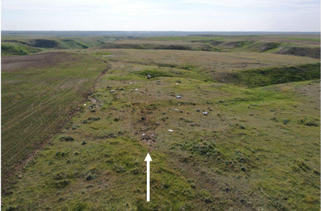 Plane crash site, looking west. The white arrow indicates the direction of flight and the initial ground impact.