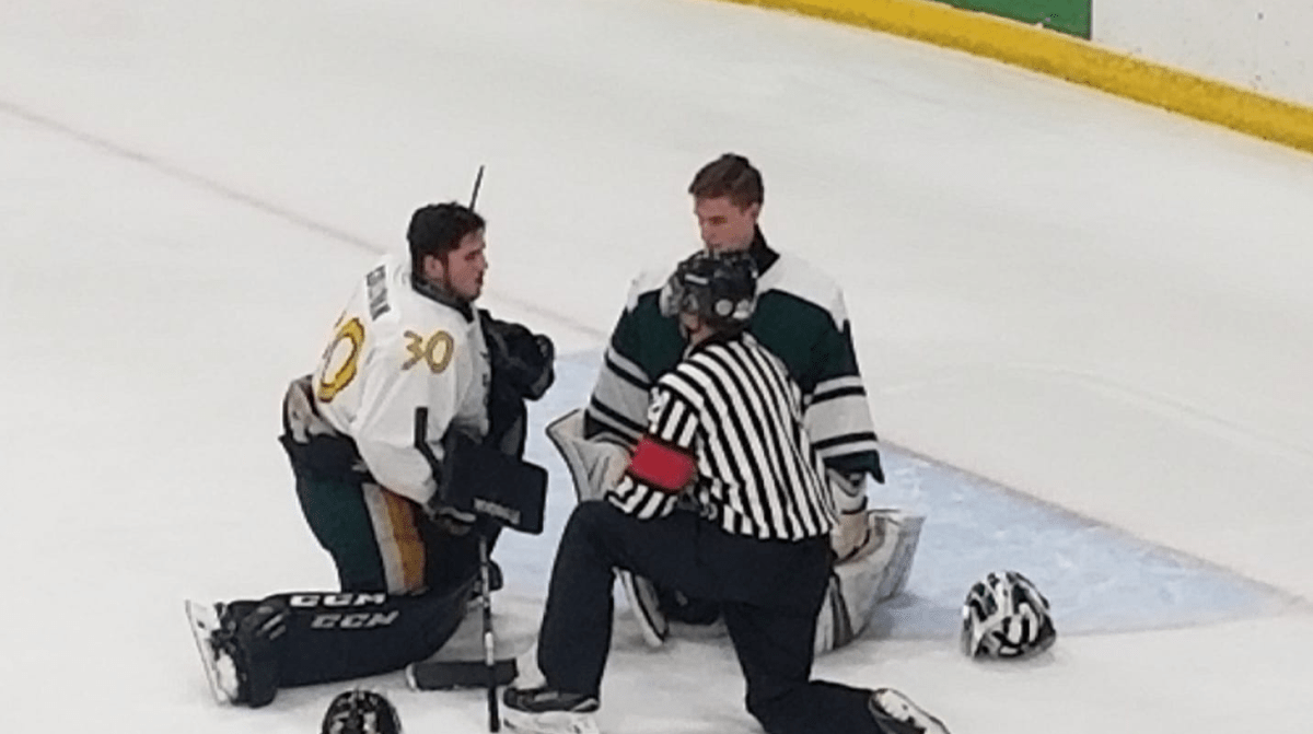 Goaltender T.J. Sullivan, left, offers tips to opposing goalie Davan Cloney during the first intermission of Saturday's high school boys hockey game.