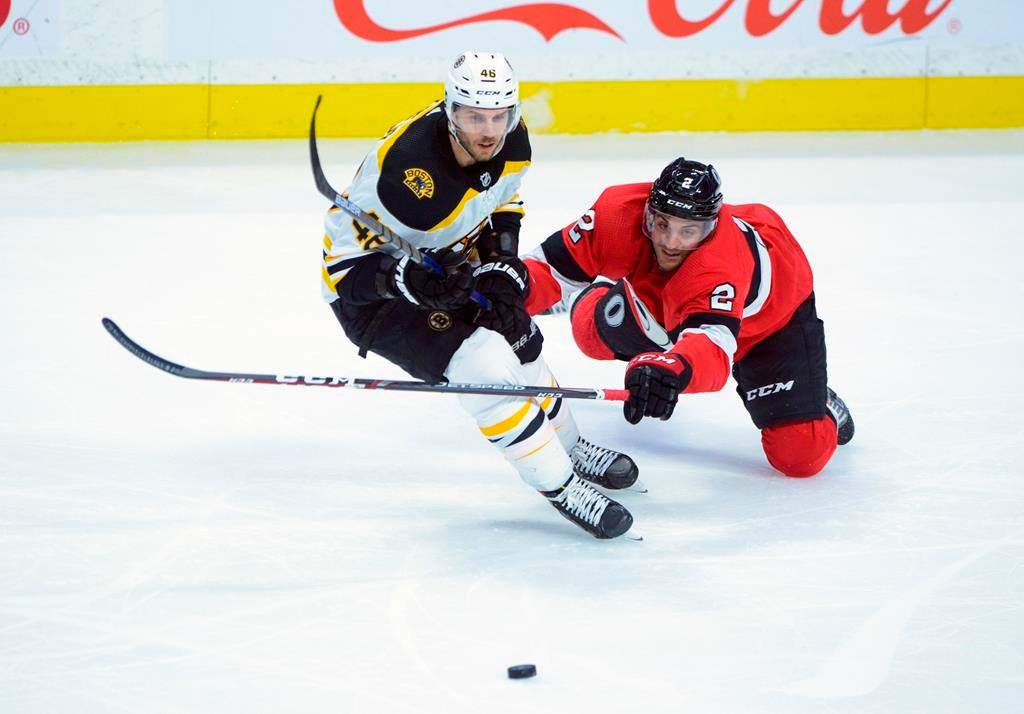 The Ottawa Senators' Dylan DeMelo dives for the puck around the Boston Bruins' David Krejci during third-period NHL action in Ottawa, Monday, Dec. 9, 2019.