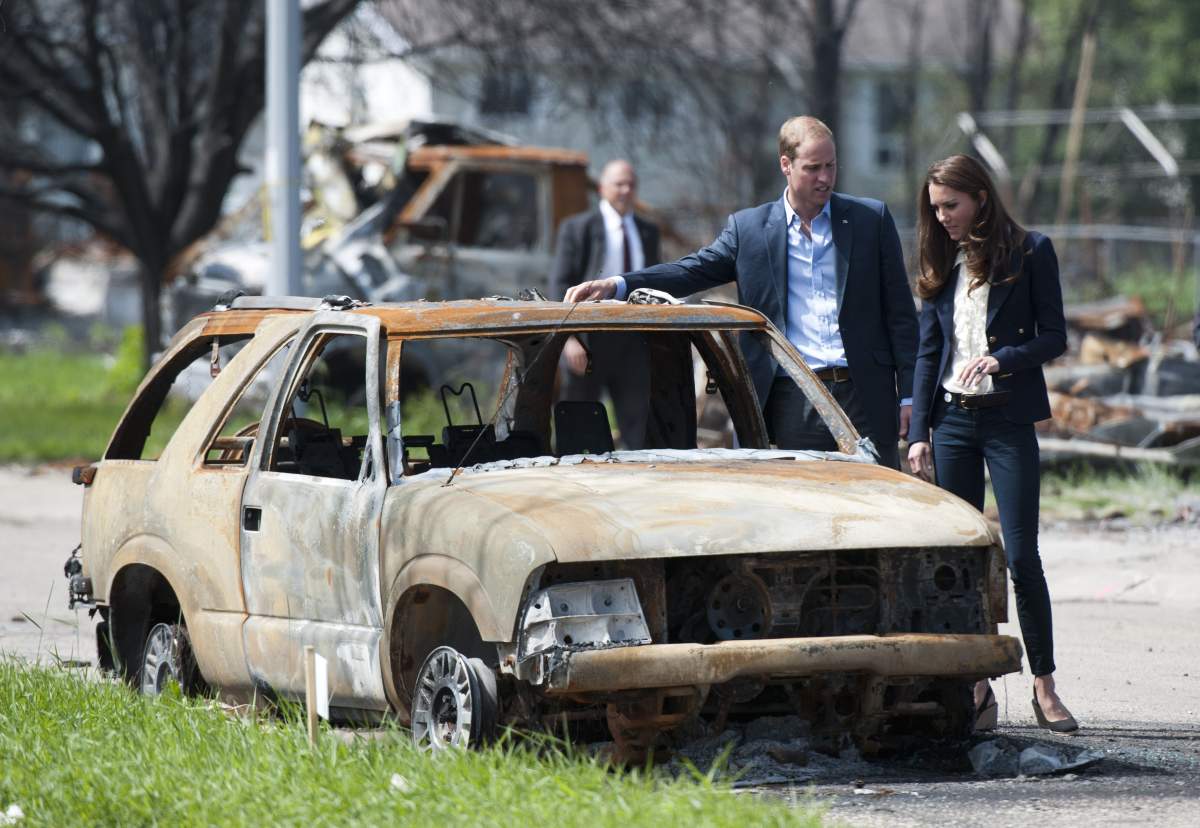 The Duke And Duchess of Cambridge inspect a fire damaged car as they walk through Slave Lake, Alta., on July 6, 2011.