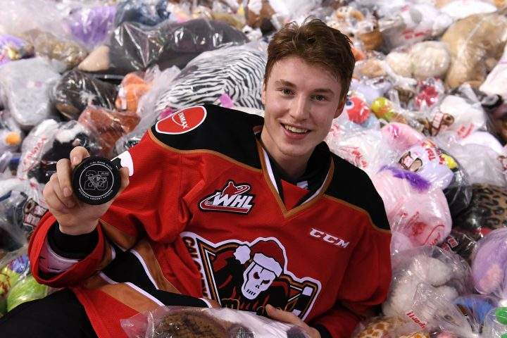 Calgary Hitmen forward Carson Focht lies in a pile of bears holding the goal-scoring puck at the 2019 Teddy Bear Toss on Sunday, Dec. 1, 2019.