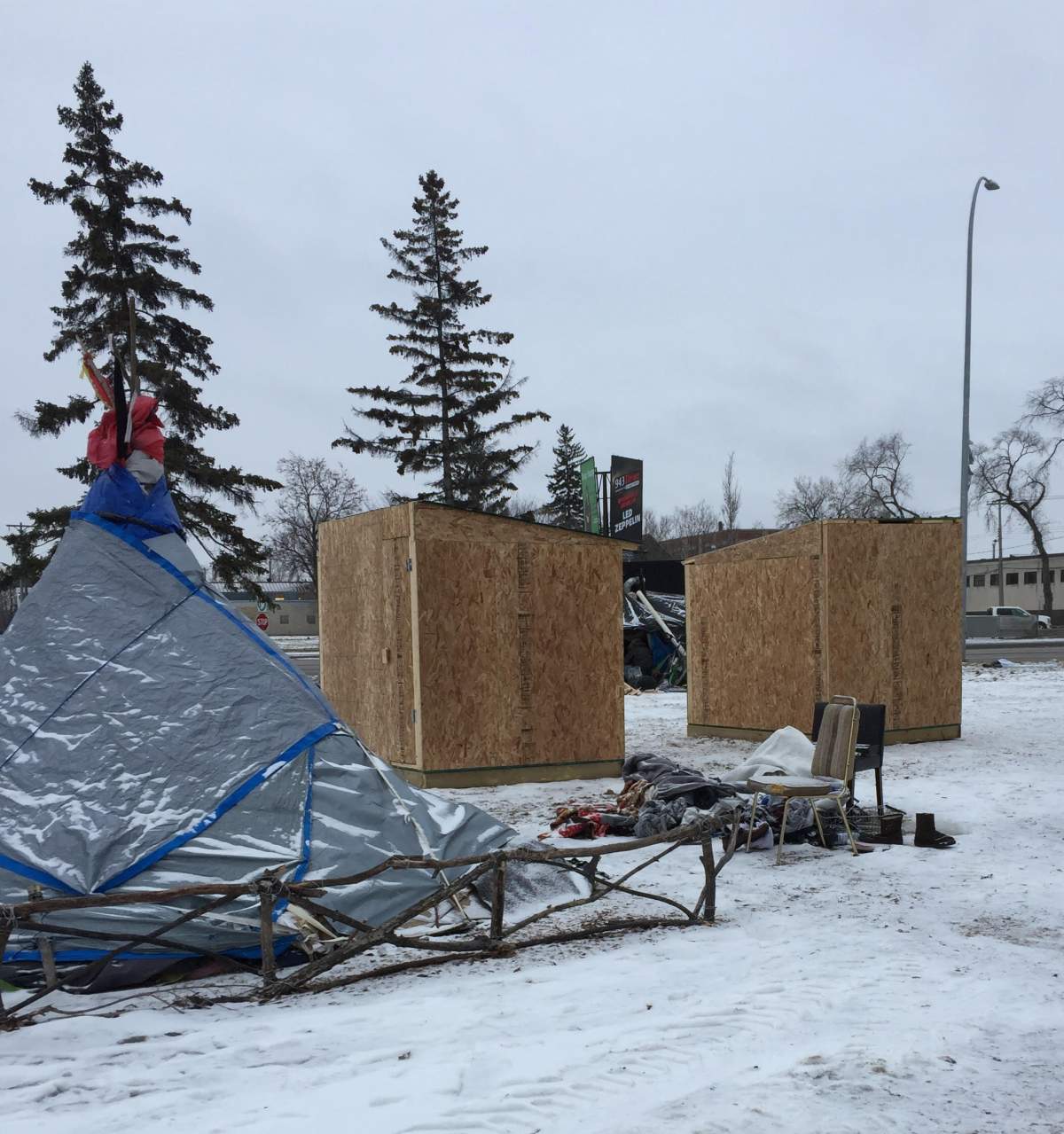 A tarp tent in front of two donated warming huts.